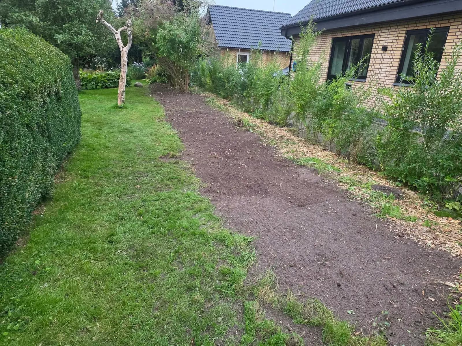 Samme areal ryddet, med jævnet bed og flis langs kanten